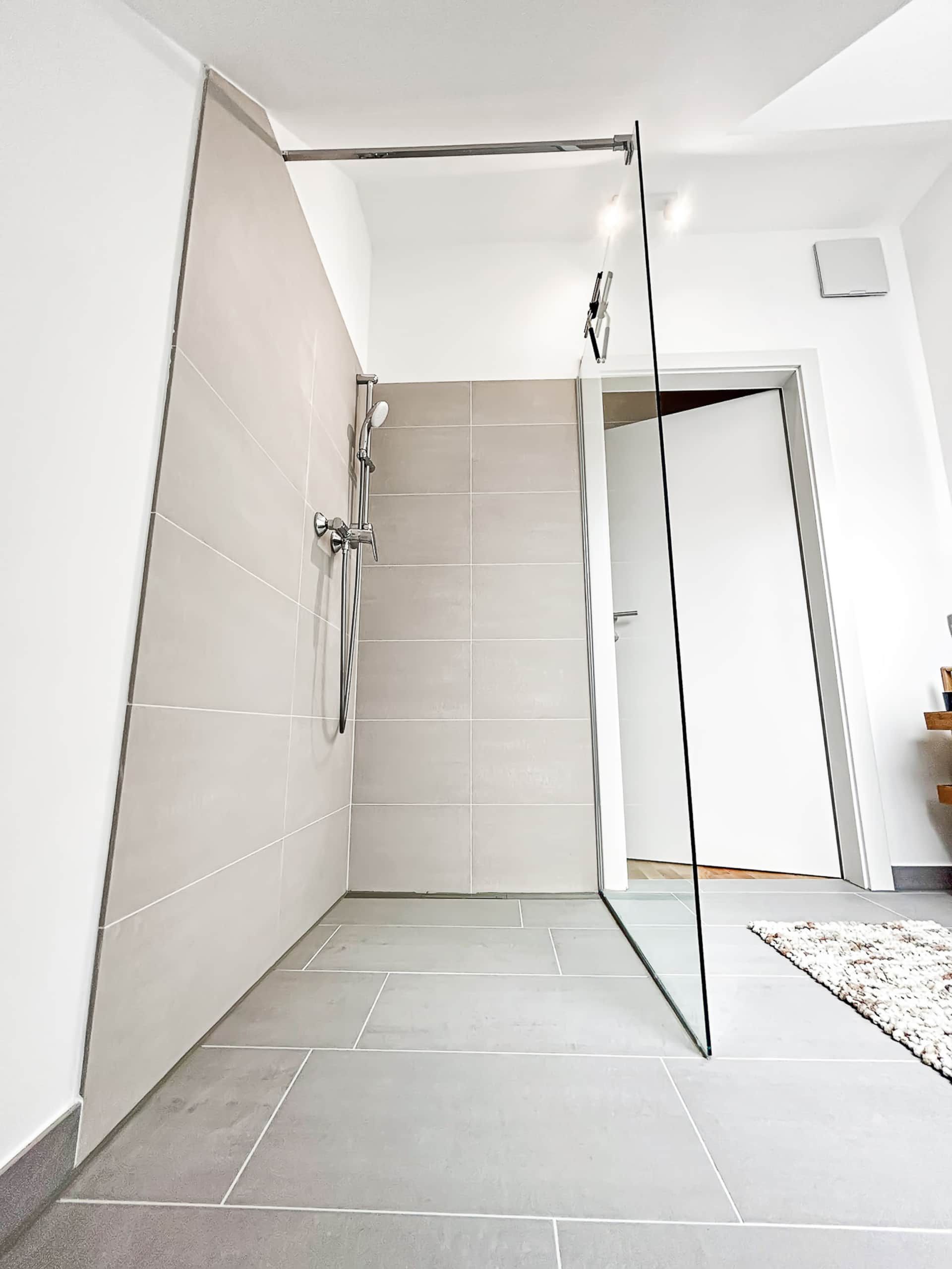 Floor-level shower with gray tiles and glass walls