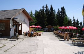 Au&szlig;enbereich der Polleresh&uuml;tte mit Sitzpl&auml;tzen und Sonnenschirmen.