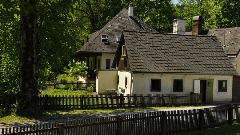 Gästehaus, © fritz fischer Ein traditionelles Gästehaus mit Holzzaun und Garten, umgeben von Bäumen.