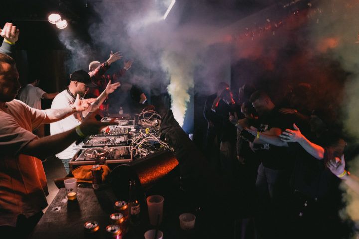 DJ-Pult mit Nebel, im  Hintergrund sind einigen Menschen 