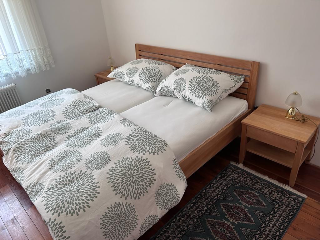 Schlafzimmer mit Doppelbett, Holzmöbeln und Teppich.