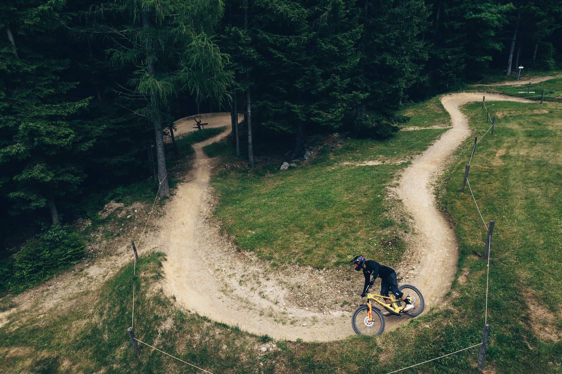 Ein Mountainbiker gleitet geschmeidig über die kurvenreiche Strecke, umgeben von dichten, grünen Wäldern. Die frische Bergluft und das Rauschen der Blätter schaffen eine perfekte Kulisse für Abenteuerlustige. Hier in den Wiener Alpen wird jeder Moment zum unvergesslichen Erlebnis.