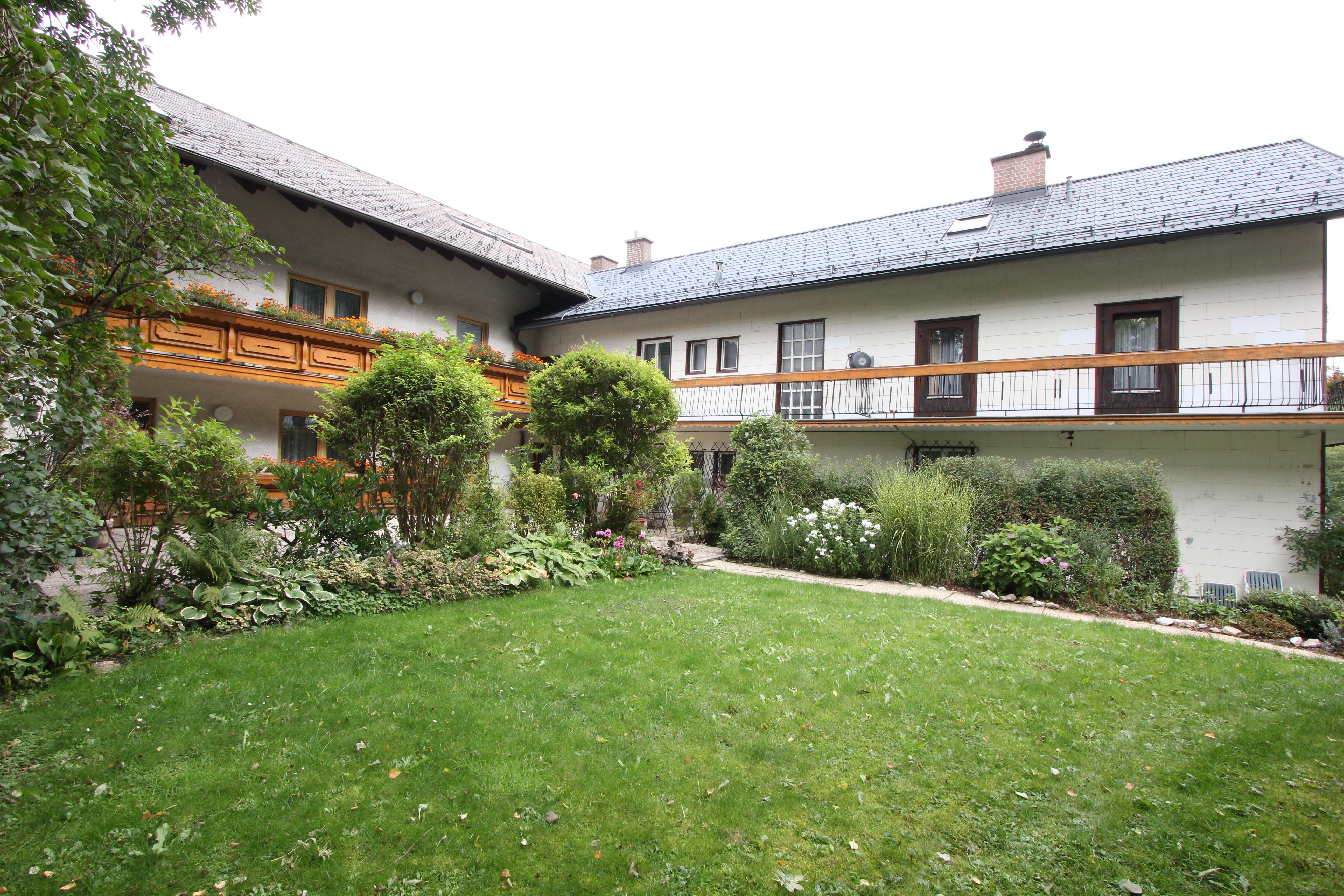 Ein traditionelles Haus mit Holzbalkon und gepflegtem Garten.