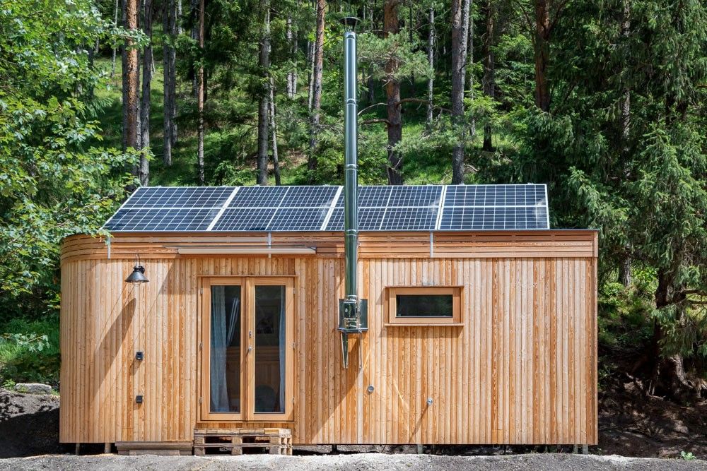 Kleines Holzhaus mit Solarpanelen auf dem Dach im Wald.