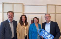 Vier Personen stehen nebeneinander und halten ein Logoschild in den Händen.