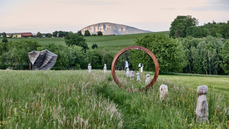 Sculpture park with works of art and mountain in the background.