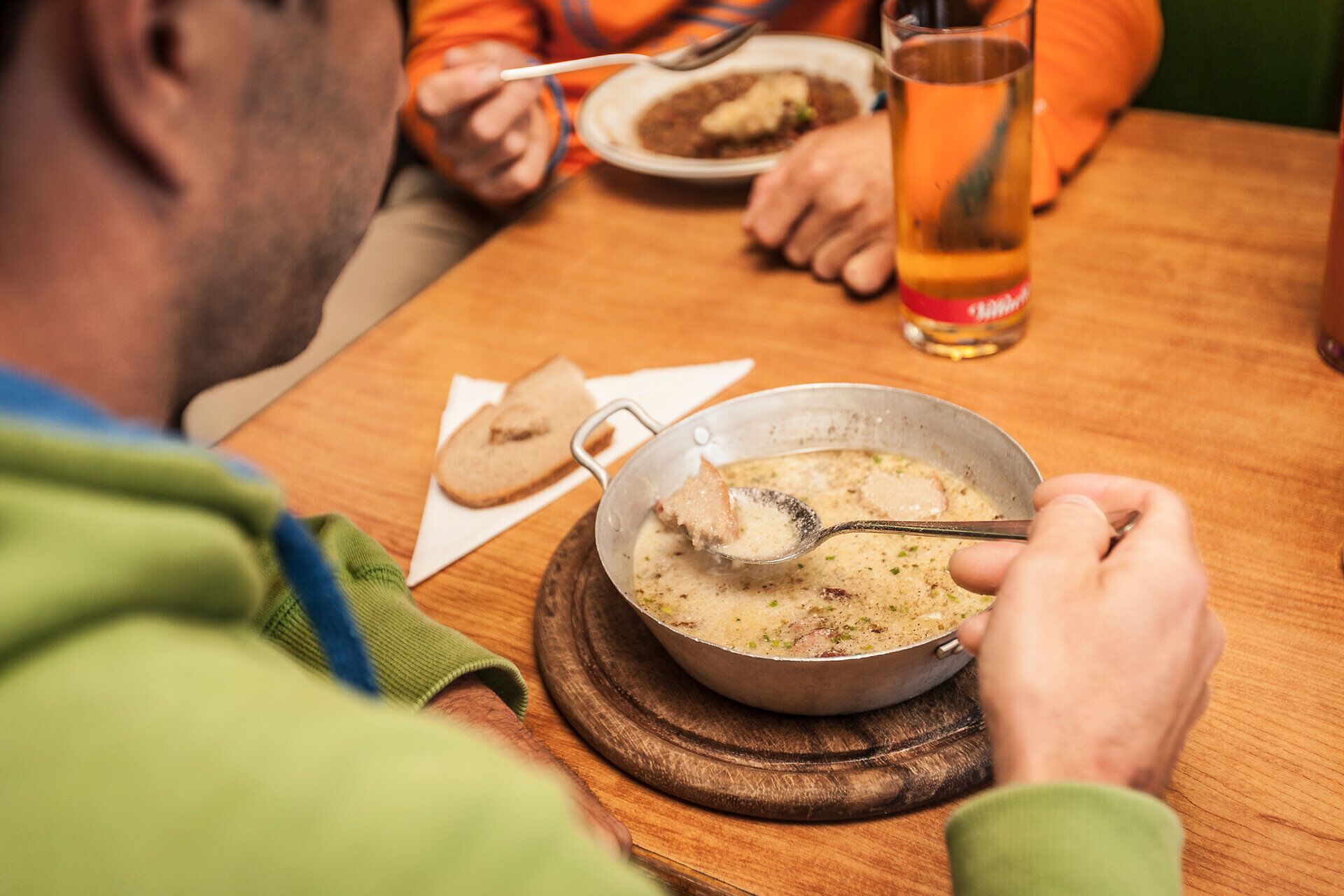 Ein herzhaftes Gericht dampft in einer rustikalen Schüssel, während die fröhlichen Gespräche der Wanderer im Hintergrund die Atmosphäre beleben. Die Kombination aus köstlicher Suppe und geselligem Beisammensein macht den Tag in den Wiener Alpen unvergesslich.