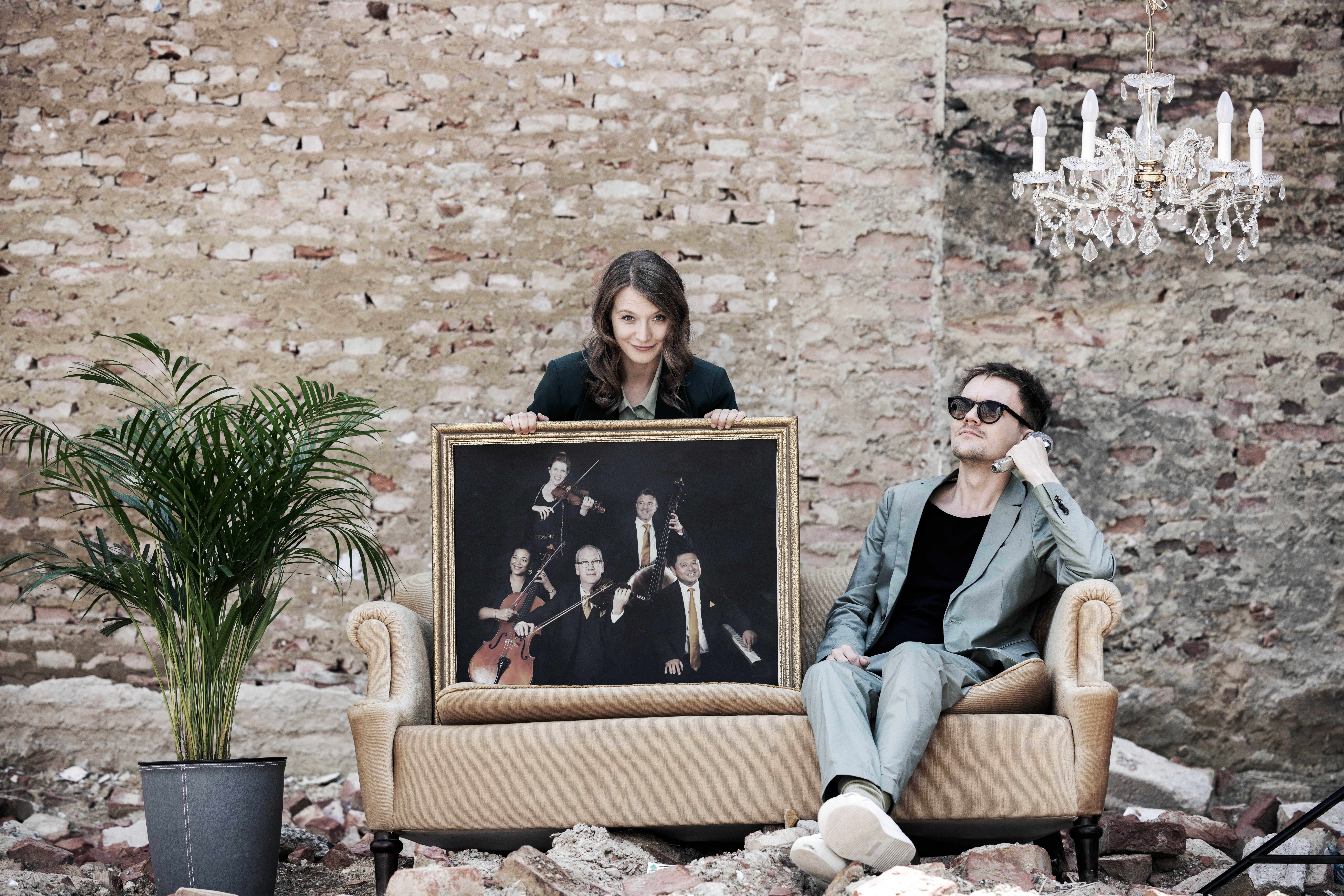 Zwei Menschen sitzen auf einem Sofa und halten ein Bild von Musikanten