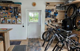 Innenansicht einer Fahrradwerkstatt mit Fahrrädern und Zubehör an den Wänden.
