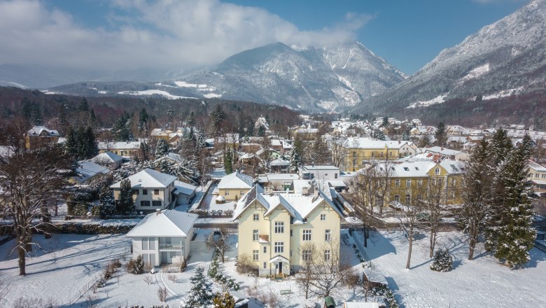 Verschneite Stadt mit Bergen im Hintergrund.