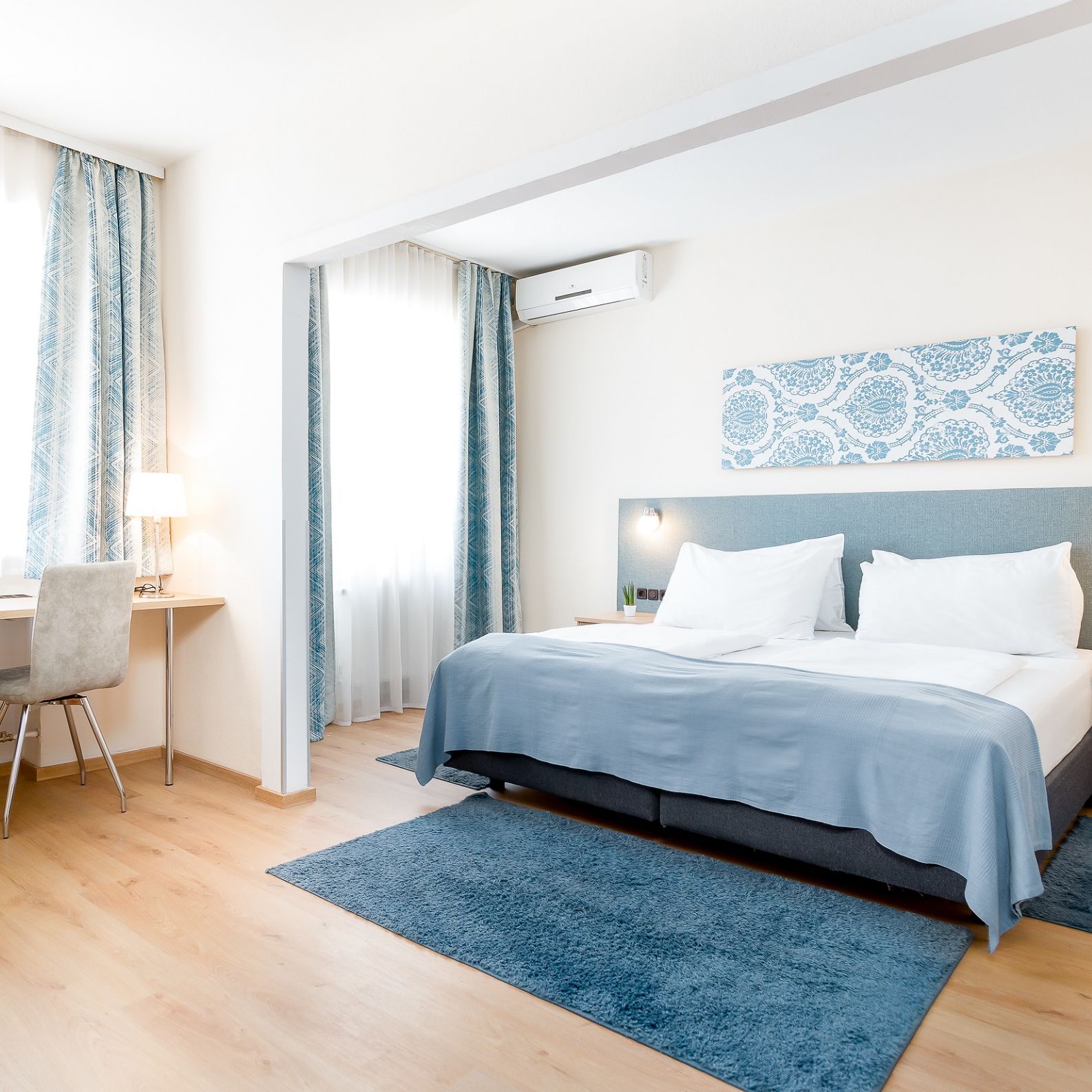 Ein Platz mit einer Säule und Statuen, umgeben von Gebäuden, darunter das Hotel Zentral.