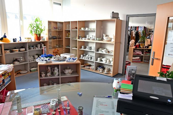 Innenansicht eines Second-Hand-Ladens mit Regalen voller Geschirr und Dekorationsartikel.