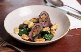 Venison roulade with chard and root vegetables, served with gnocchi on a plate.