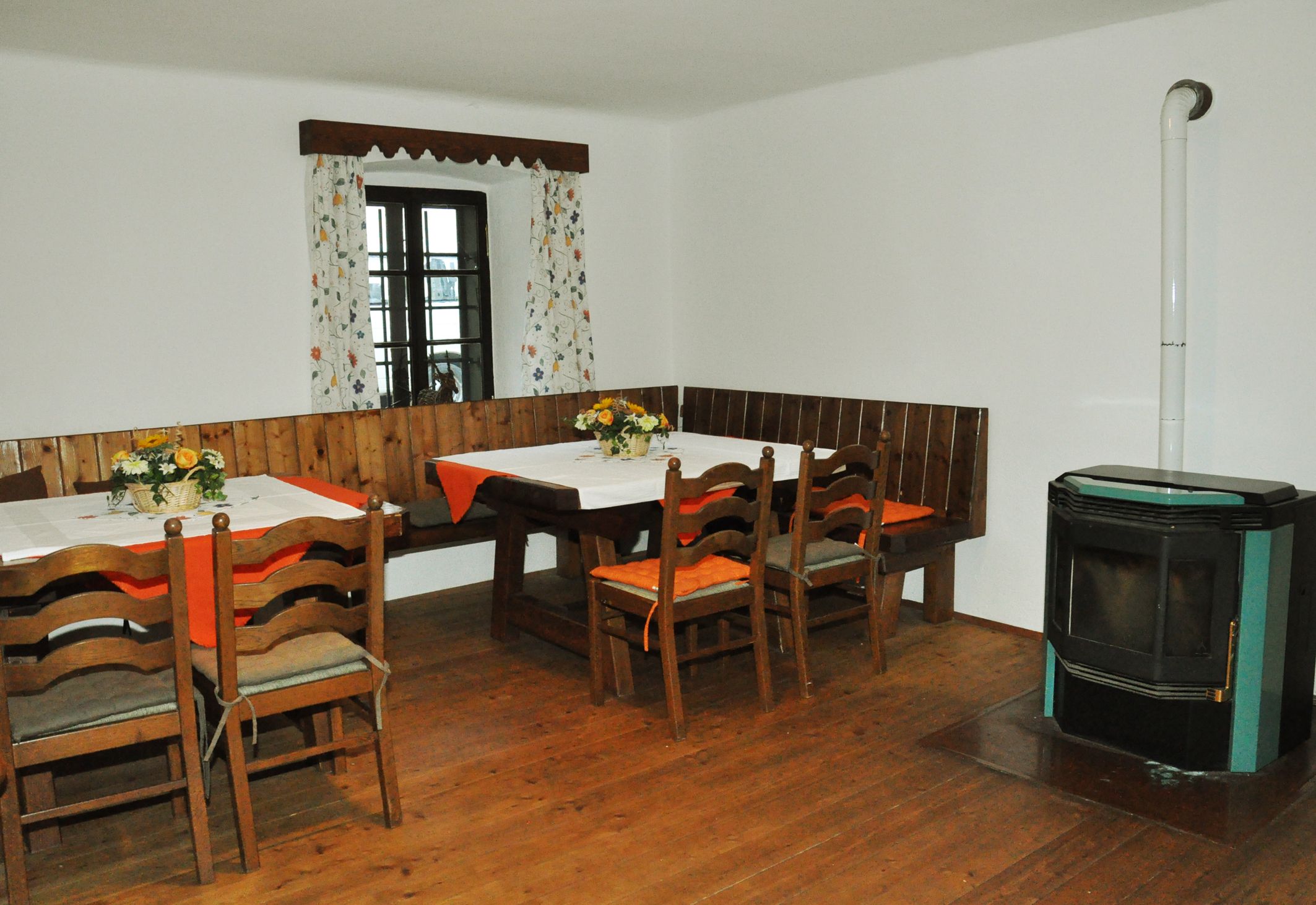 Gemütlicher Essbereich mit Holztisch, Stühlen, Eckbank und Ofen.