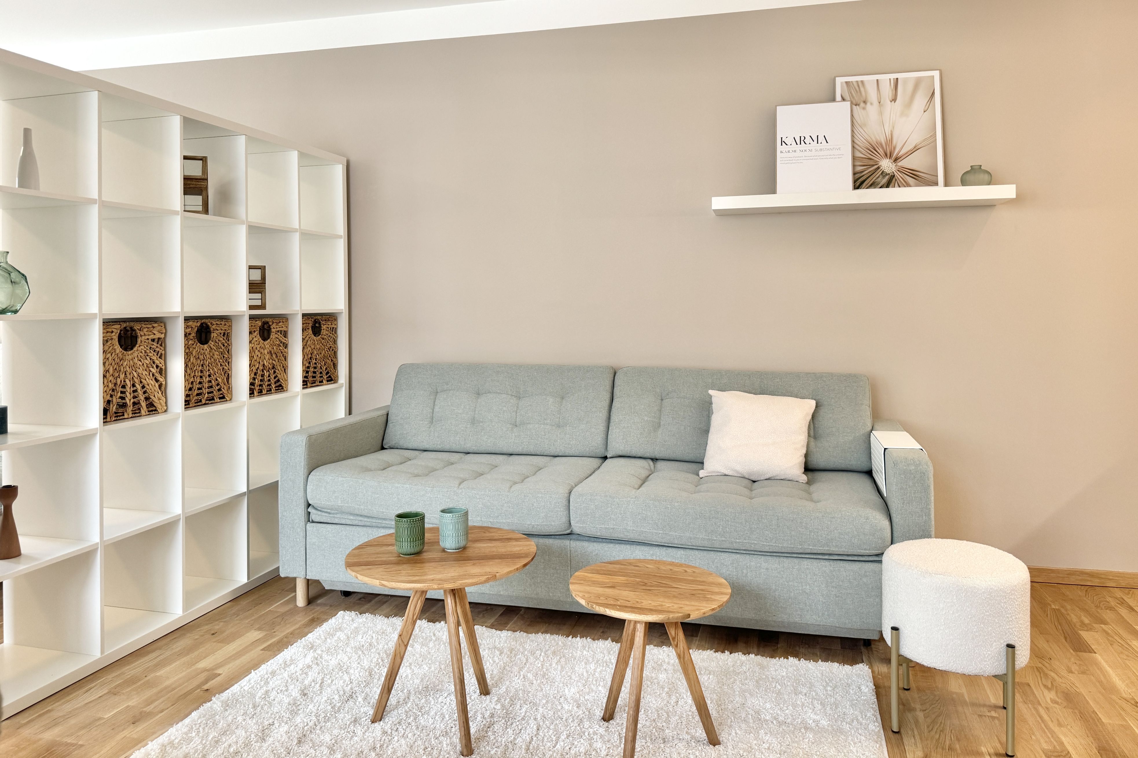 Helles Wohnzimmer mit grauer Couch, Raumteiler und beigen Wänden