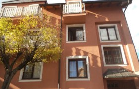 Außenansicht eines dreistöckigen Hauses mit orangefarbener Fassade und weißen Fensterrahmen.