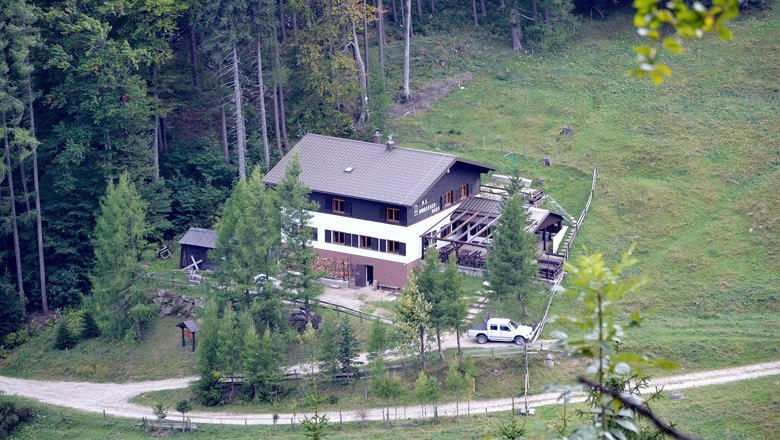 Himbergerhaus, © Naturfreunde Himberg / Alfred Sedivy Ein großes Haus im Wald mit einem Auto davor, umgeben von Bäumen und Wiesen.