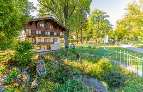 Miniaturhaus in einem Park mit Bäumen und einem Weg.