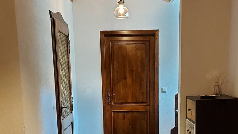 Ein Flur mit Holztüren, Holzdecke und modernen Lampen.