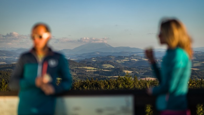 Verschwommene Personen vor einer klaren Berglandschaft im Hintergrund. Zu sehen ist der Schneeberg