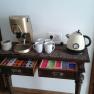 Coffee machine and kettle on a table with cups and tea bags.