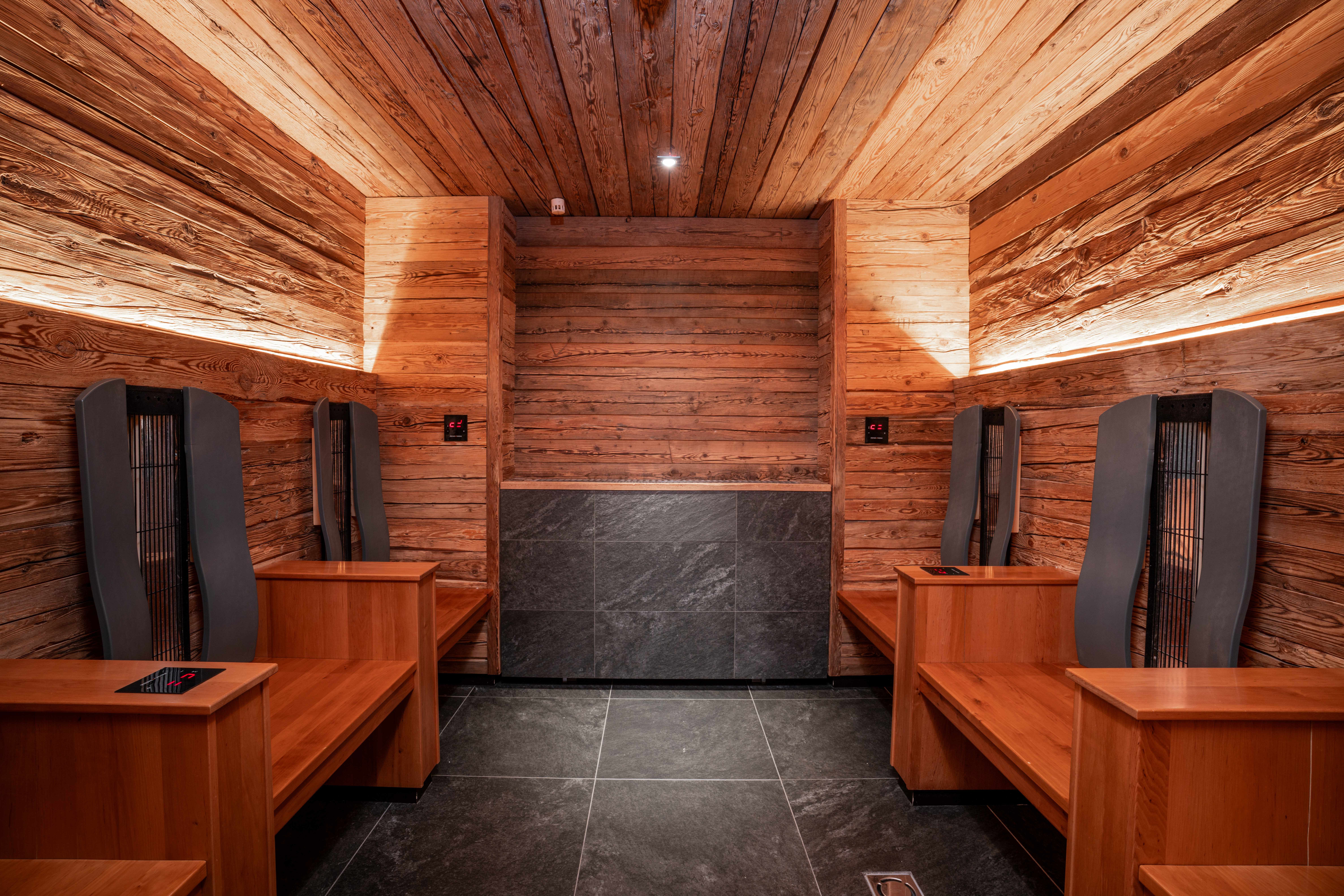 Innenansicht einer modernen Sauna mit Holzwänden und Sitzbänken.