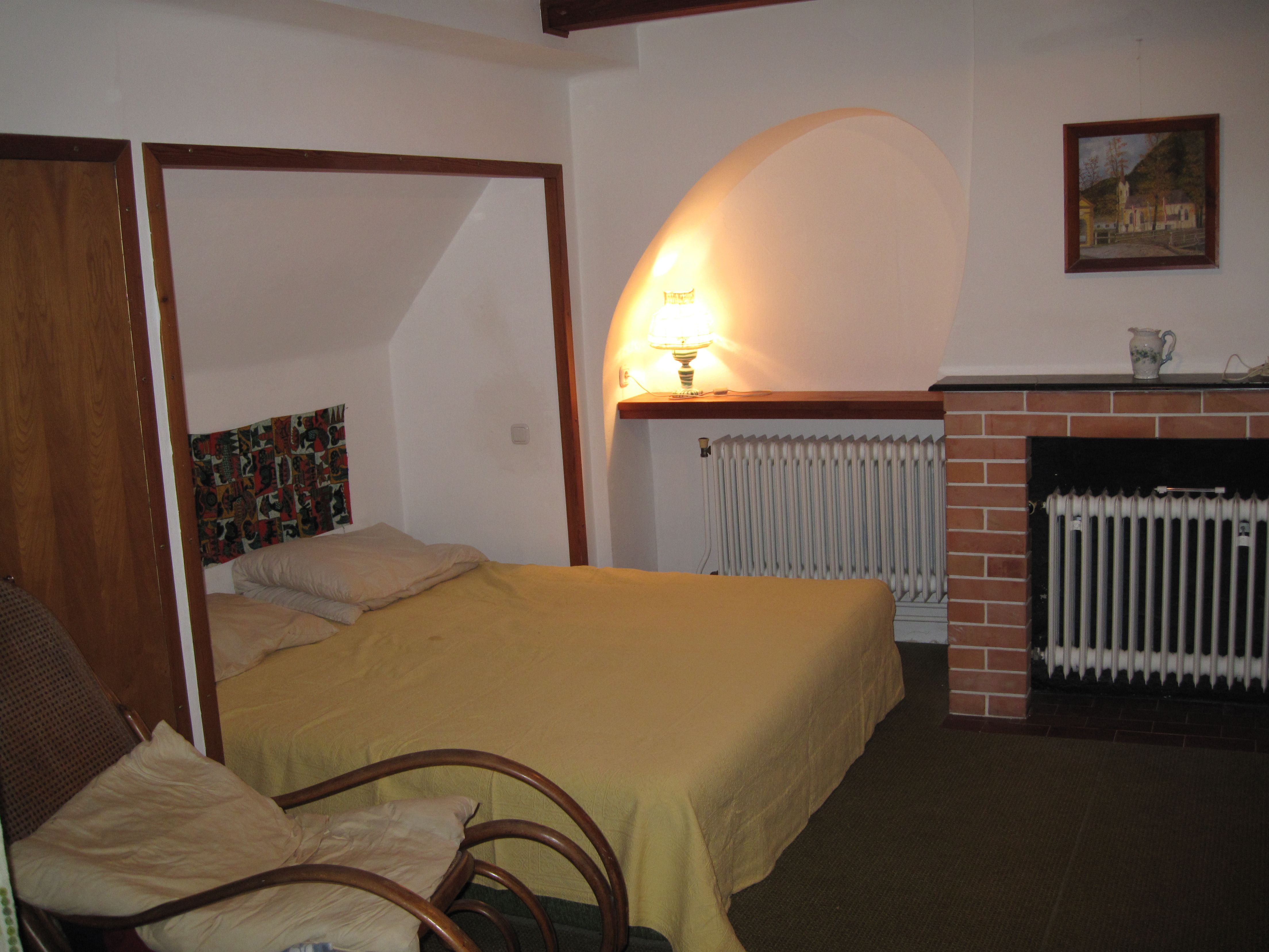 Ein gemütliches Schlafzimmer mit einem Bett, einem Sessel, einer Lampe und einem Kamin.