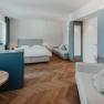 Modern furnished hotel room with double bed, sofa and wooden floor.