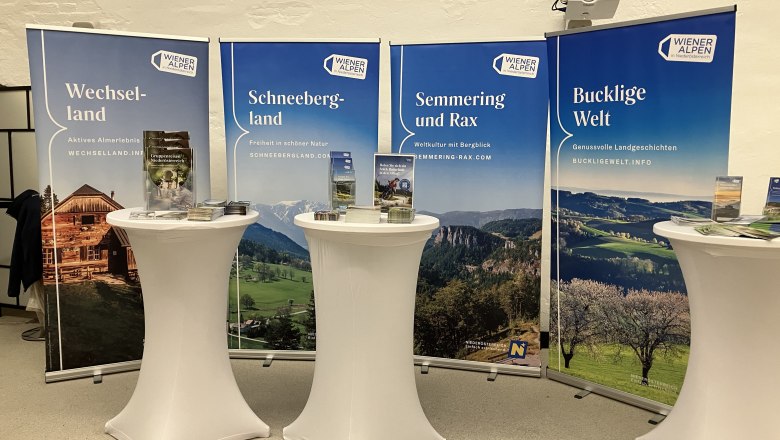 4 Rollups hinter 3 Stehtische, die Rollups sind mit Verschiedenen Fotos hinterlegt 