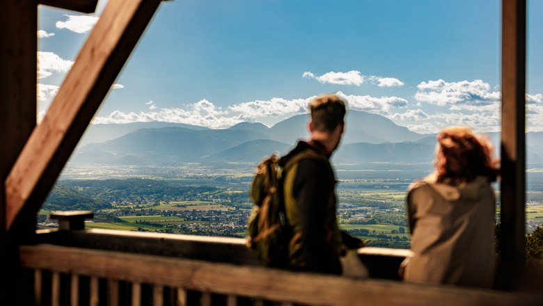Zwei Personen stehen auf der Plattform des h&ouml;lzernen Aussichtsturmes Lanzenkirchen/Wiesen, im Hintergrund ist eine weite Ebene und am Horizont der Schneeberg gut erkennbar.