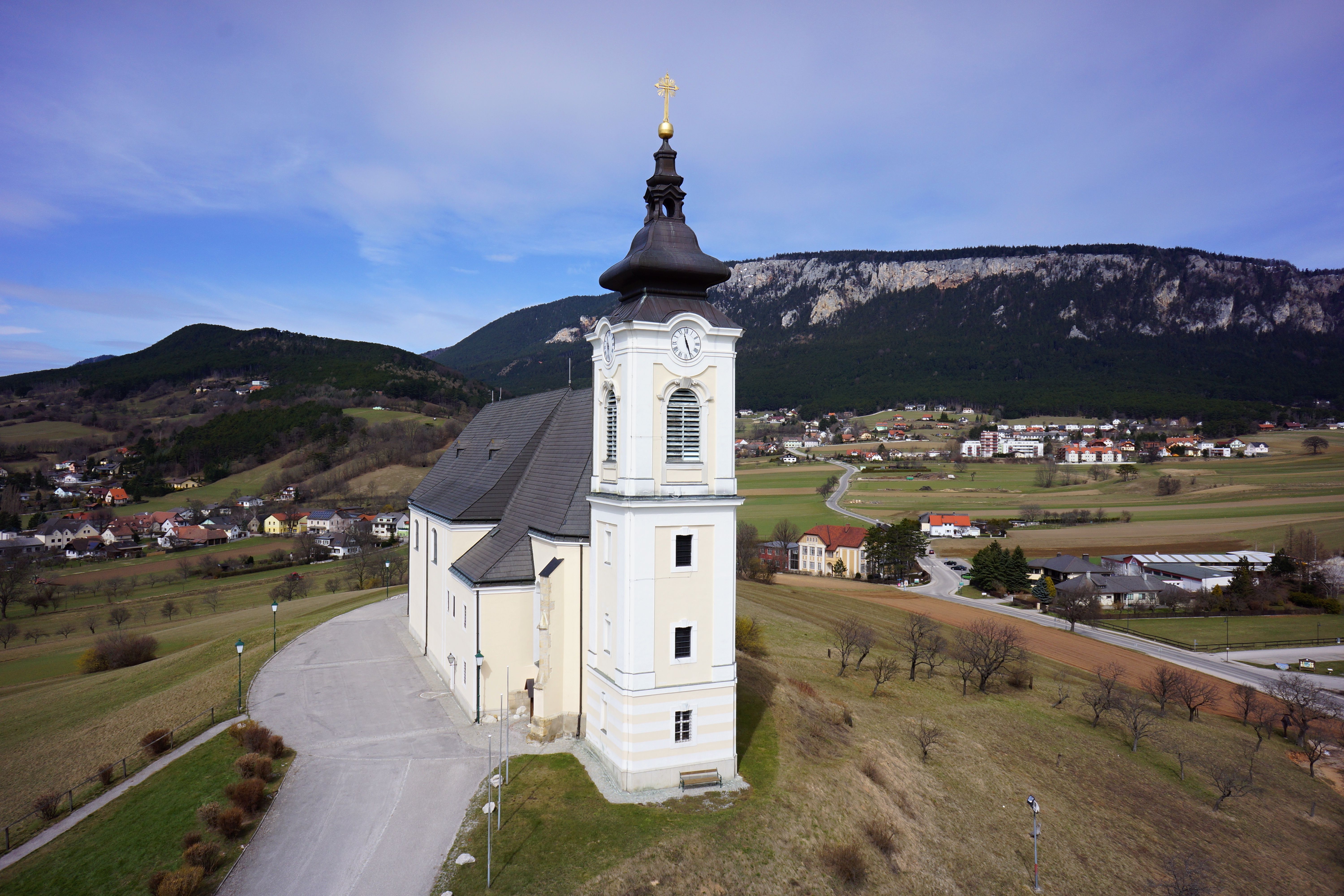 Barocke Kirche in ländlicher Landschaft mit Blick auf die Hohe Wand im Hintergrund