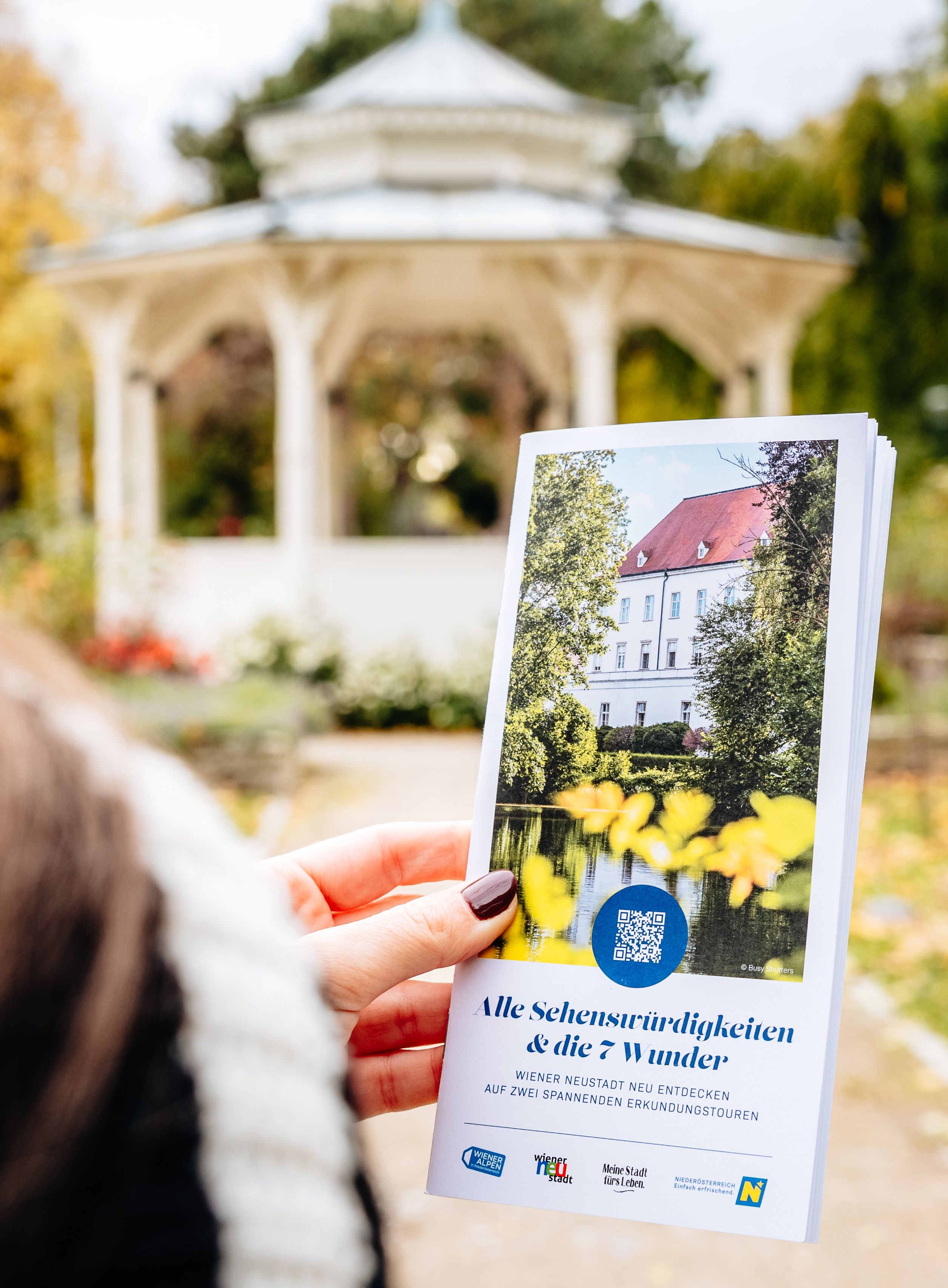 Frau mit Flyer vor einem Pavillon. 