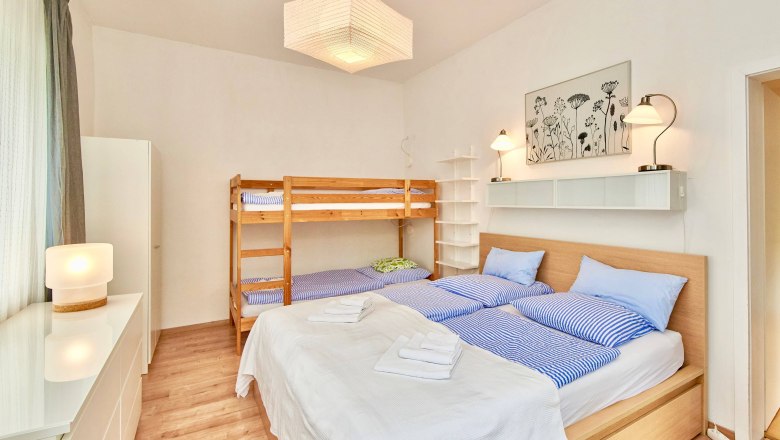 Bedroom with double bed and bunk bed, bright furnishings.