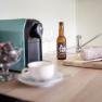 Kitchen worktop with coffee machine, beer bottle, salami and knife.