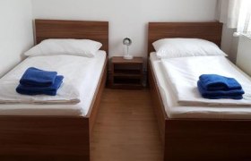 Zwei Einzelbetten in einem Zimmer mit Wanddekoration und blauen Handtüchern.