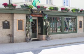 Entrance to a pub with a green façade and flower boxes.