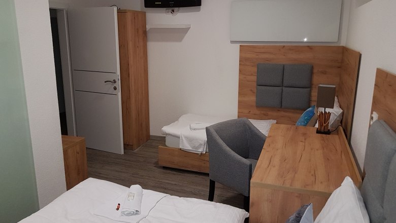 Hotelzimmer mit Holzm&ouml;beln, zwei Betten, einem Schreibtisch und einem Fernseher an der Wand.