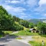 Landscape with road, house and mountains in the background.