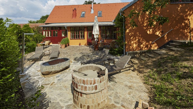 Terrasse einer Villa mit Liegestühlen und Feuerstelle.