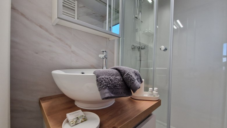 Modern bathroom with washbasin, mirror and shower.