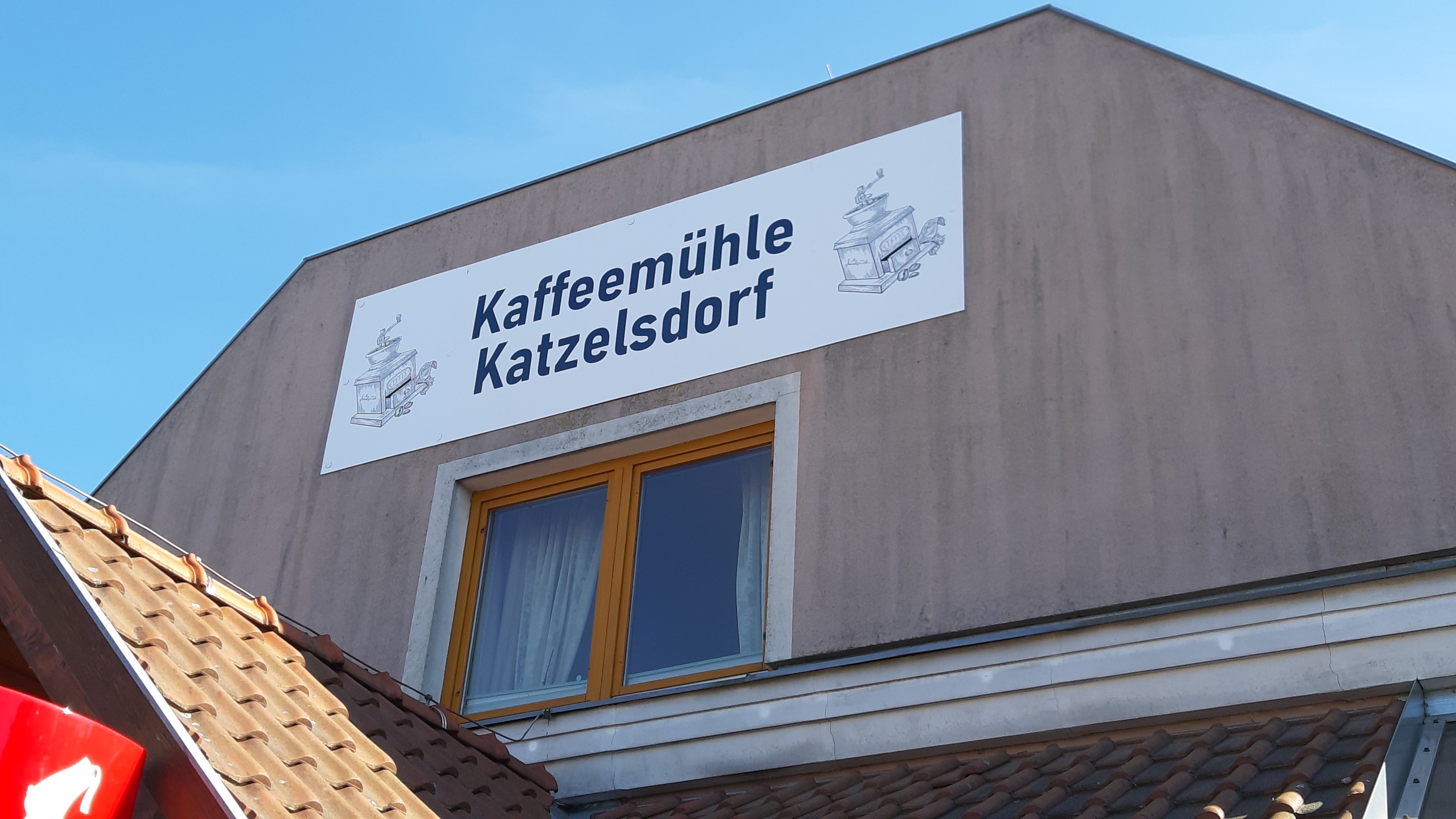 Gebäude mit Schild 'Kaffeemühle Katzelsdorf' und Zeichnung einer Kaffeemühle.