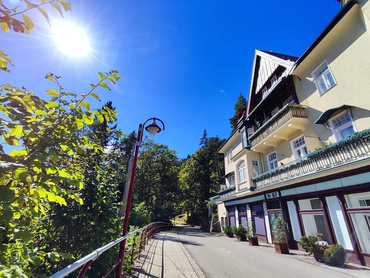 Sonniger Tag vor einer Villa mit Balkon und Bäumen.