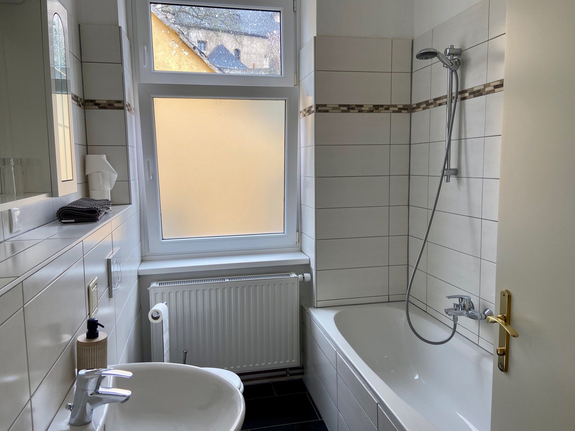 Modernes Badezimmer mit Badewanne, Waschbecken und Fenster.