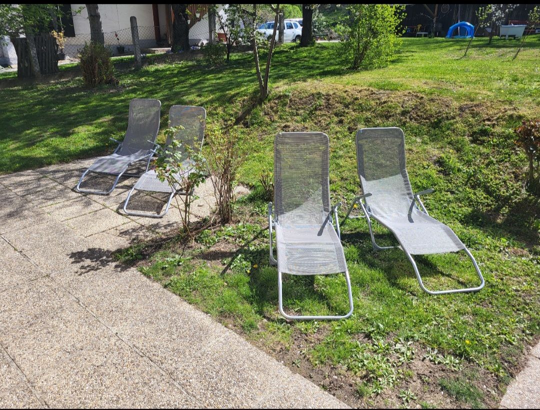 Vier Liegestühle auf einer Terrasse im Garten.
