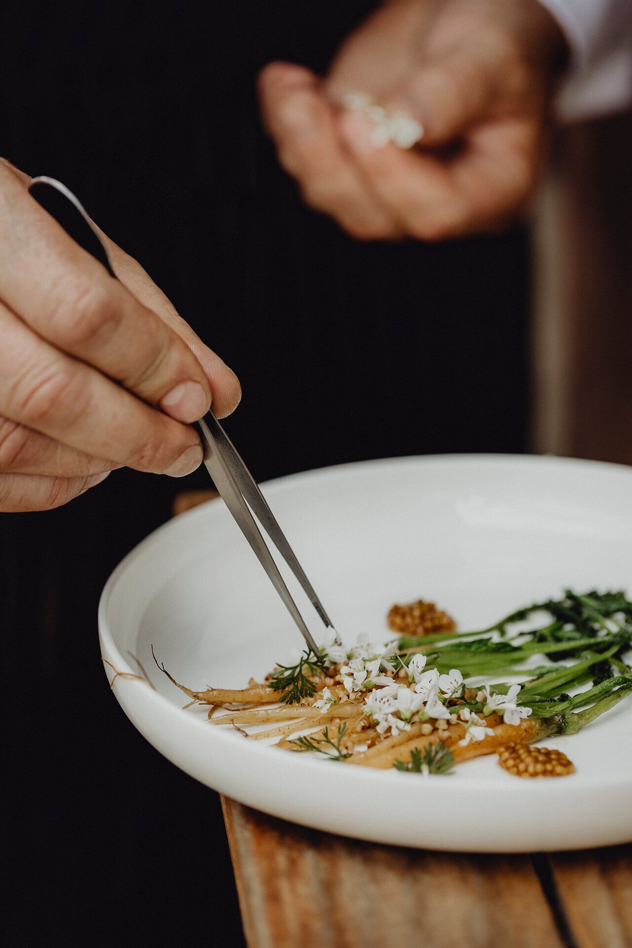 Ein kunstvoll angerichteter Teller präsentiert geschmorte Karotten, umgeben von zarten Brunnenkresseblüten und feinem Senfkaviar. Die harmonische Komposition aus frischen Zutaten und kreativer Präsentation lädt dazu ein, die Aromen der Region zu entdecken und zu genießen. Ein kulinarisches Erlebnis, das die Wirtshauskultur in Niederösterreich lebendig werden lässt.