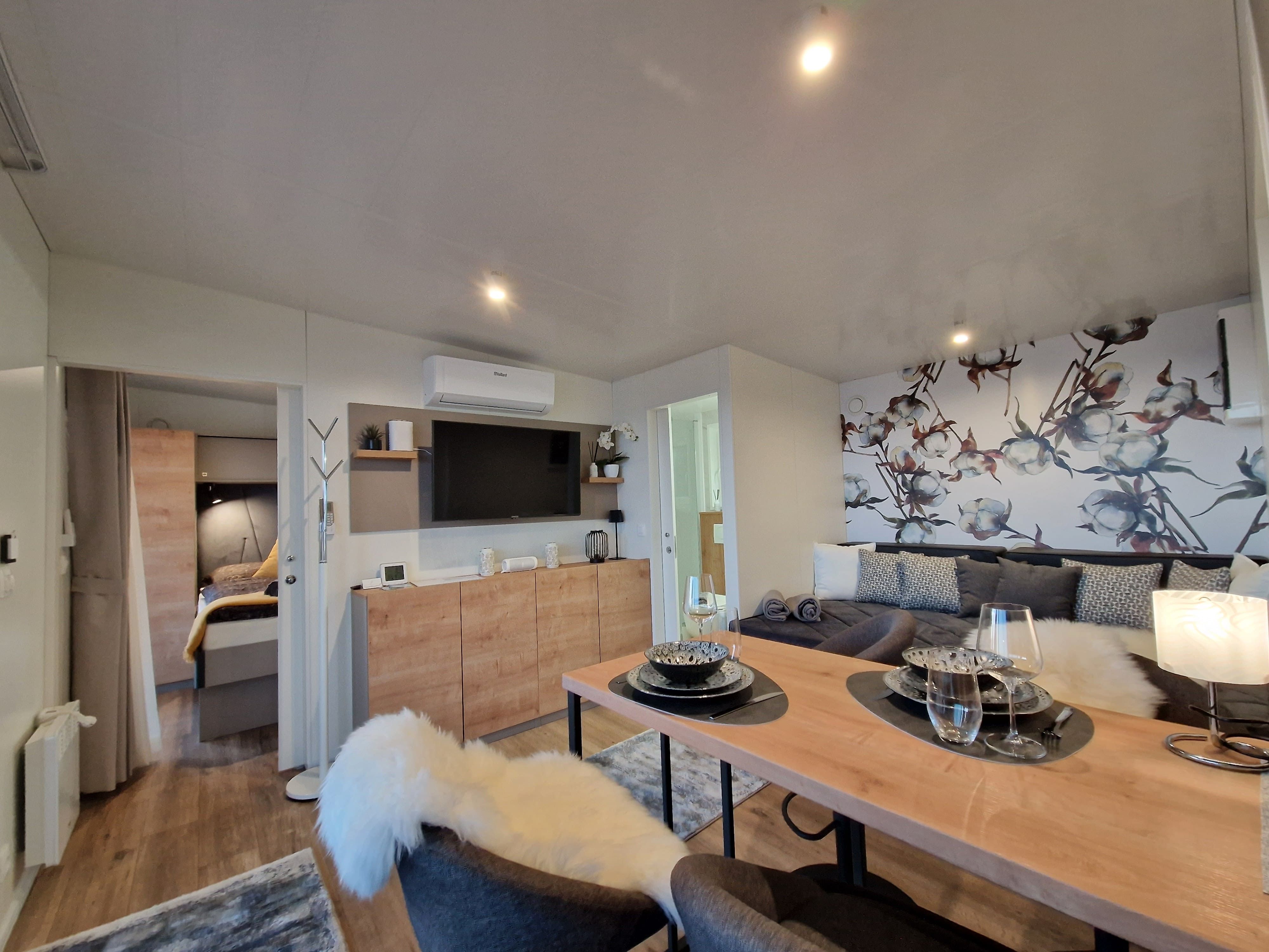 Modernes Wohnzimmer mit Esstisch, Sofa und dekorativer Wand.