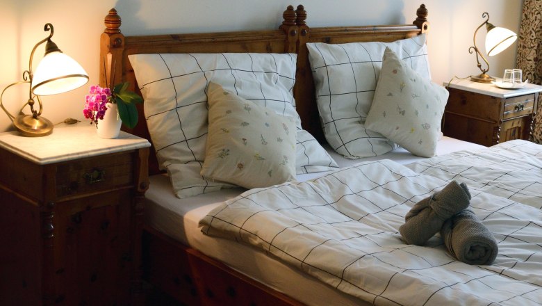 Cozy double room with wooden furniture, bed with checkered bedding, bedside tables and lamps.