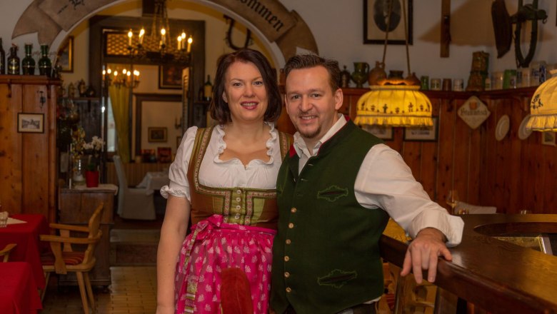 Ein Paar in traditioneller bayerischer Tracht in einem rustikalen Gasthaus.