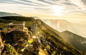 Die goldenen Strahlen der Sonne brechen durch die Wolken und tauchen die majestätischen Berge in ein warmes Licht. Ein atemberaubender Ausblick auf die sanften Hügel und dichten Wälder lädt dazu ein, die frische Bergluft zu genießen und die Seele baumeln zu lassen.
