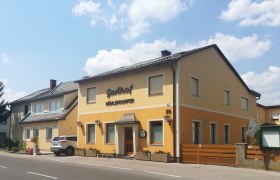 Ein gelbes Gebäude mit der Aufschrift 'Gasthof Mühlendorfer' an einer Straße.